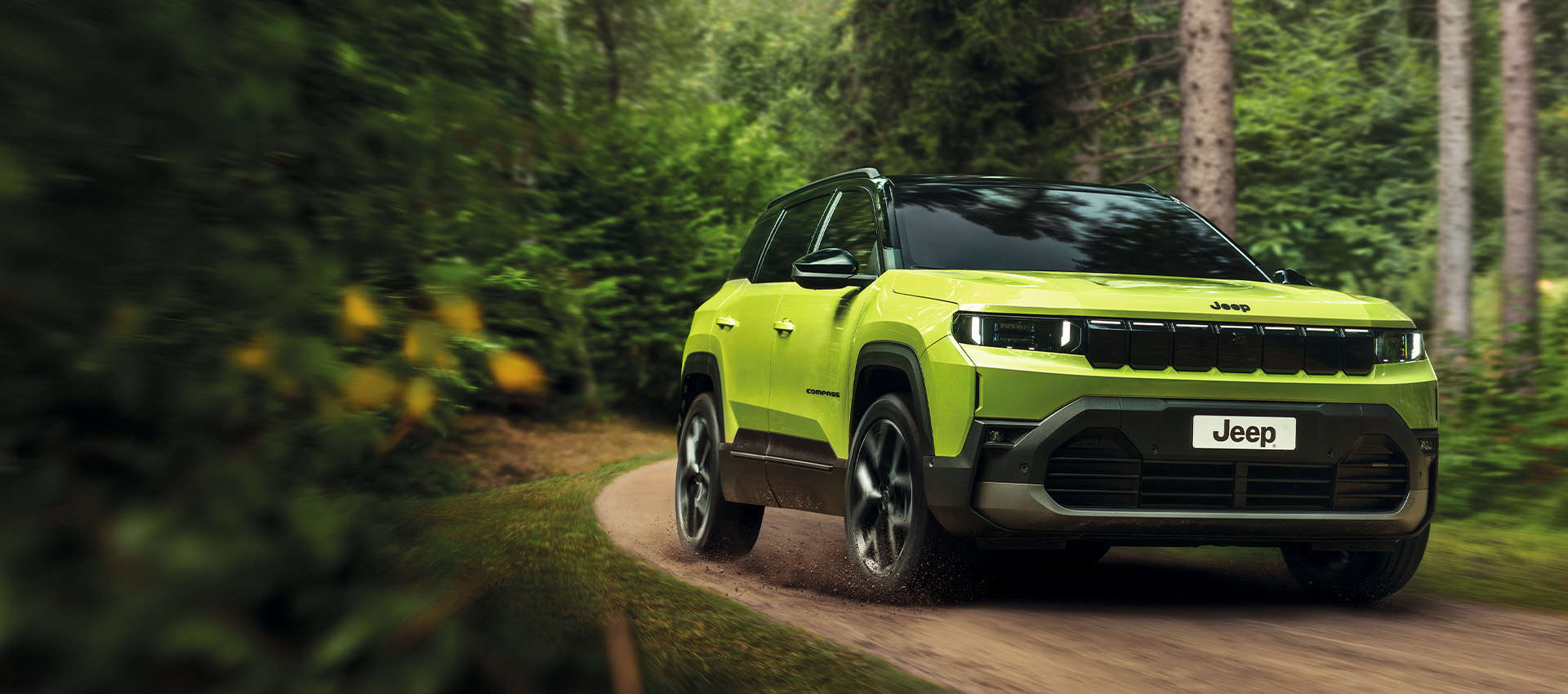 Jeep Compass e-Hybrid їде по ґрунтовій дорозі у лісі