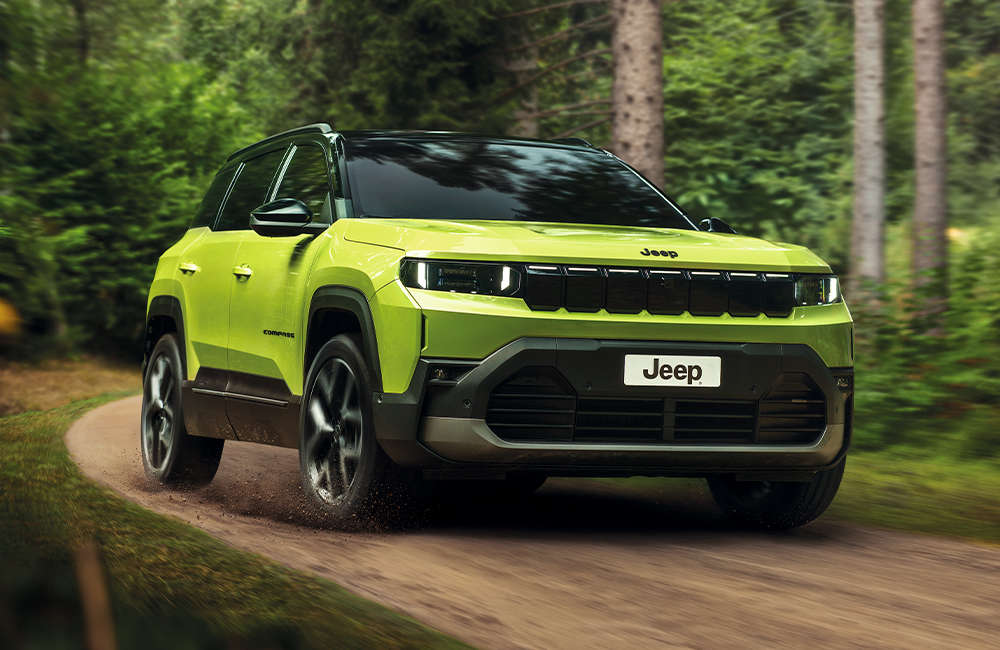Jeep Compass e-Hybrid їде по ґрунтовій дорозі у лісі