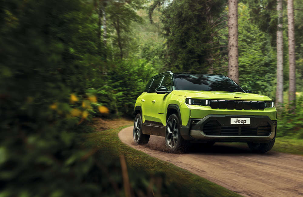 Jeep Compass e-Hybrid їде по ґрунтовій дорозі у лісі